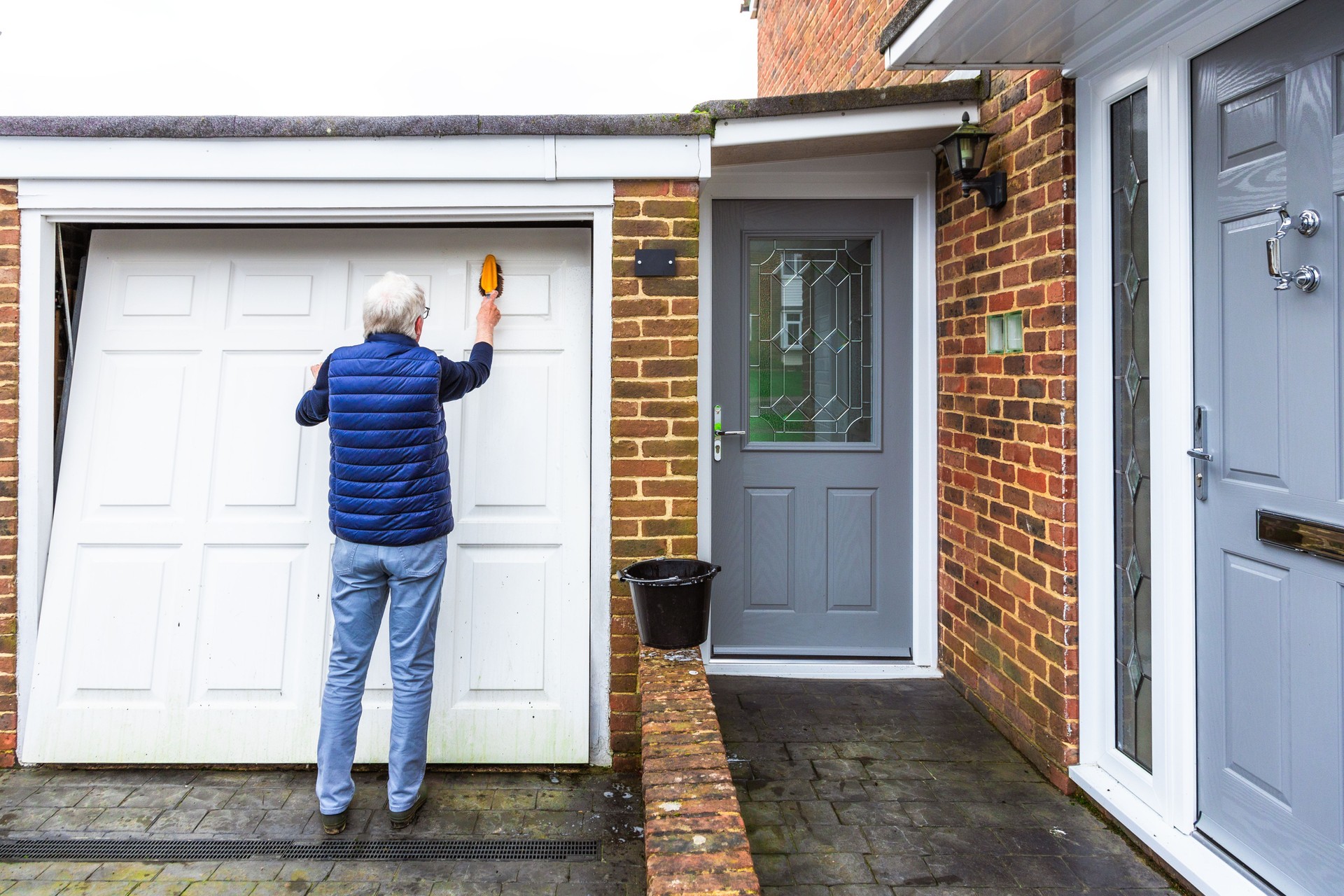 Senior man cleaning dirty garage door at home
